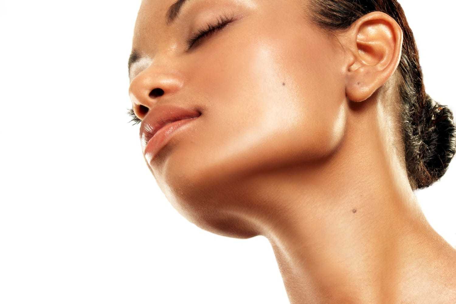 A close-up of a woman's serene face with glowing skin against a white background.