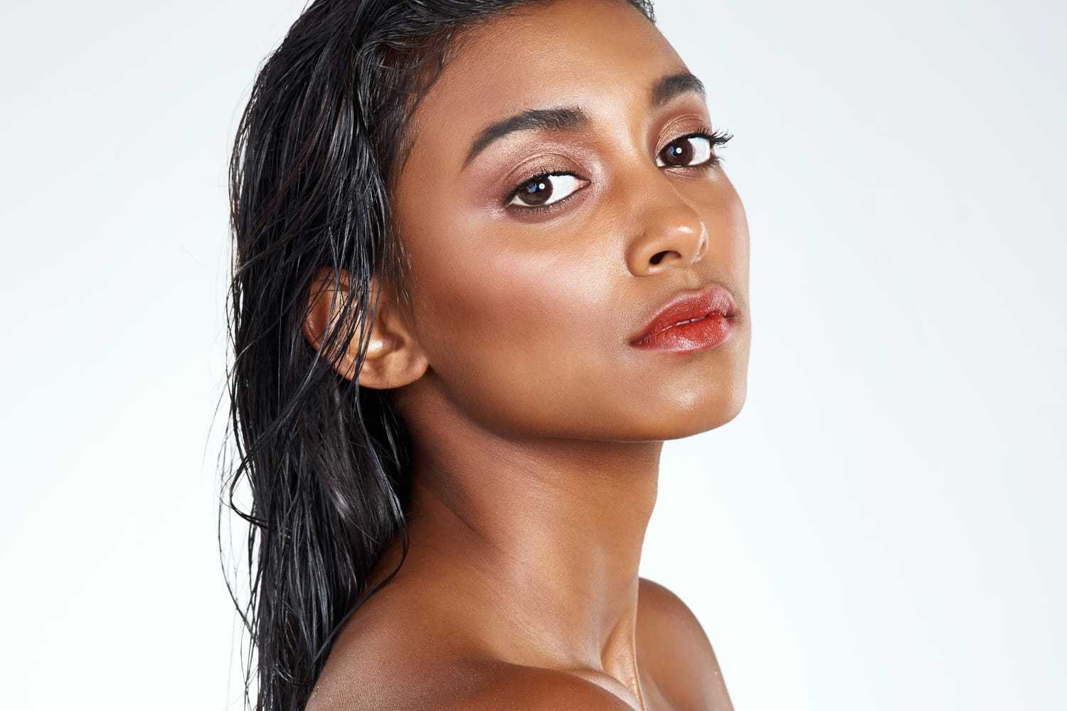 Portrait of a woman with wet hair, looking confidently at the camera against a white background.