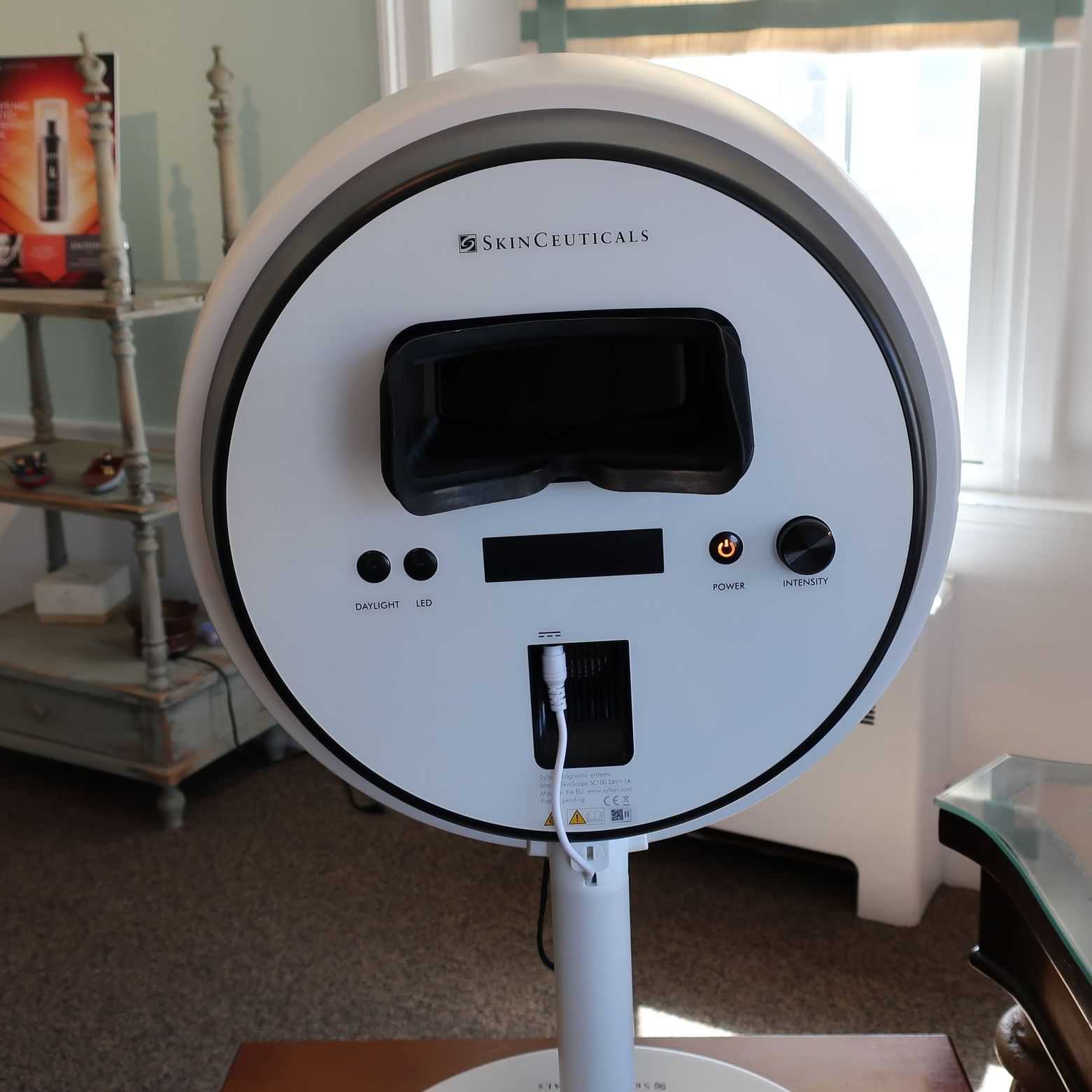 SkinCeuticals skin analysis machine with various settings buttons and a modern stand in a room.