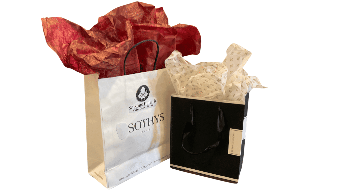 Two gift bags with tissue paper, one white and the other black, adorned with elegant logos.